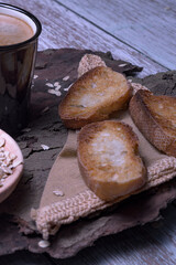 Black mug with coffee foam on tree bark, with a bowl of rolled oats and crispy toasted bread, rustic style