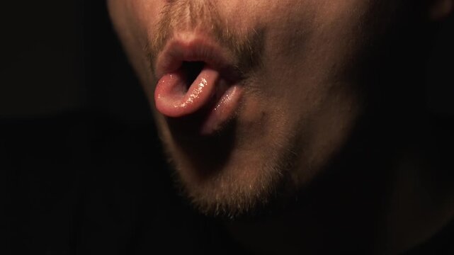 A man who has cowered aggressively moves his tongue.
An indecent tongue gesture.
A man teases and sticks out his tongue at the camera.