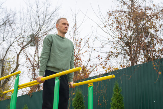 Man exercising on outdoor parallel bars in autumn