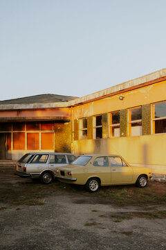 Vintage cars parked in front of an old yellow building