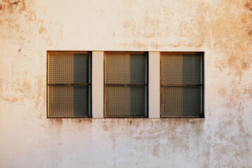 Aged building facade with three barred windows