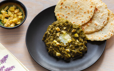 Sarson ka saag (mustard greens puree) with butter and ginger served alongside makki ki roti (cornmeal flatbread), a popular North Indian main course often prepared during winter. 