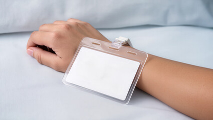 Wristband with blank identification card in critical condition resting on white fabric surface showing calm and neutral mood