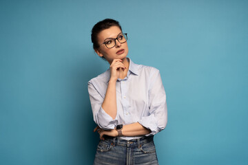 Successful employee pensive business woman, lost in thought and conjectures isolated on blue background