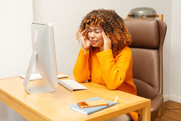 Young Black woman suffering from headache while working in modern office