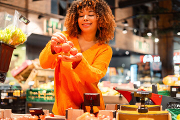 Fototapeta premium Woman choosing fresh tomatoes in grocery store for healthy eating and diet