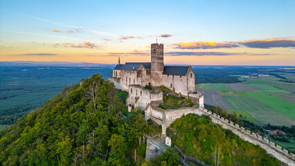 Nestled atop a hill, Bezdez Castle showcases its medieval ruins against a vibrant sunset backdrop.
