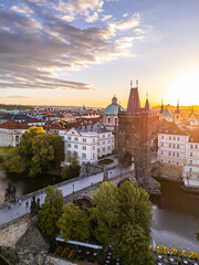 Sunset casts a warm glow on the Old Town Bridge Tower at Charles Bridge in Prague. The scenic view highlights the historic architecture and the Vltava River below, creating a charming atmosphere.