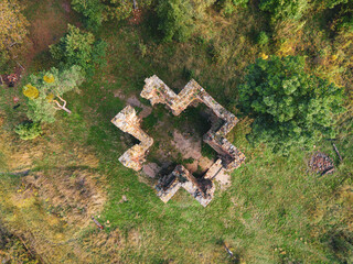 Aerial view of the Chapel of the Exaltation of the Holy Cross in Bristev. The stone ruins stand amidst lush greenery, showcasing historical architecture and natural beauty during daylight.