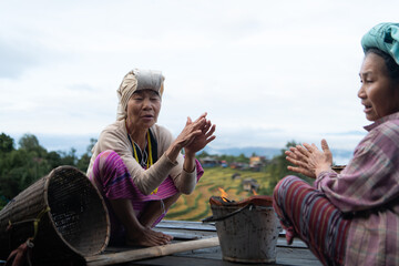 Two Asian rural women sitting together on a wooden platform