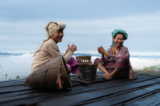 Two Asian rural women sitting together on a wooden platform