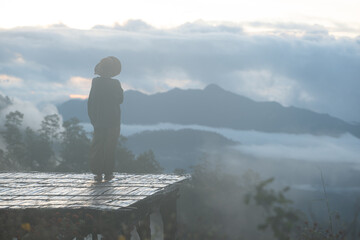 Silhouette of a traveler standing quietly on a wooden platform at sunrise