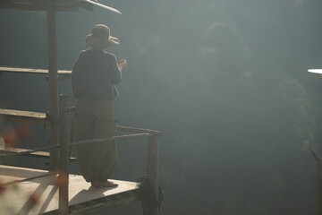 Naklejka premium Silhouette of a person resting on a wooden balcony overlooking misty mountains