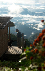 Naklejka premium Simple mountain cabin with a traveler and dog overlooking a sea of clouds
