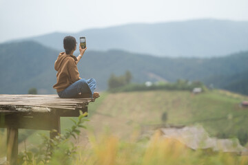 Asian woman taking photos with smartphone on a wooden platform