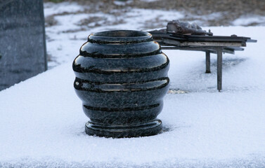 Black granite memorial vase on snow covered grave