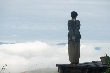 Person practicing yoga tree pose on a wooden platform above clouds