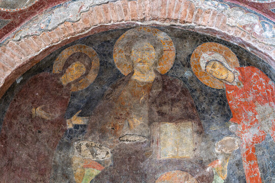 Italy - Rome - Temple of Romulus - Closeup of an ancient Christian fresco featuring three saints adorned with golden halos, a religious artwork.