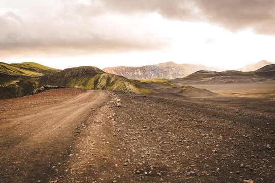 View of a rugged path cuts through a stark, volcanic landscape under a brooding sky, showcasing nature's raw beauty, Landmannalaugar, The Central Highland, Iceland.