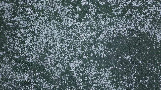 Top-down aerial drone view of a frozen lake surface with natural ice patterns and textures, winter background with calm and minimal atmosphere.