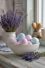 Fototapeta premium Pastel Easter eggs in a white bowl on a weathered wooden table, with lavender sprigs in the foreground. Concept Pastel Easter Eggs, White Ceramic Bowl, Weathered Wood Table, Lavender Foreground