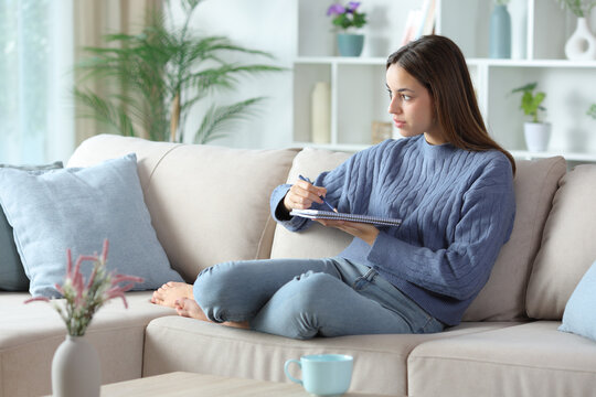 Woman in blue drawing on notebook at home