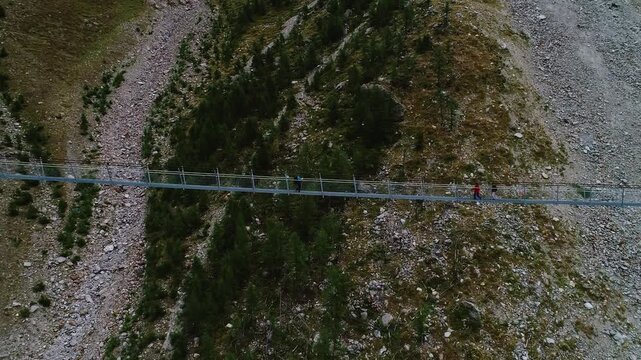 Three hikers cross the Charles Kuonen Suspension Bridge as drone flies back