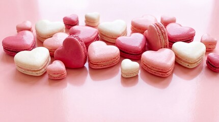 Assortment of heart shaped pink and white macarons arranged in a flat lay composition