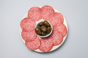Thinly sliced salami sausage on a plate, top view