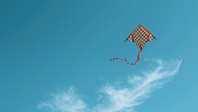 Vibrant kite flying high against a bright blue sky with a decorative spiral tail, ideal for layout backgrounds