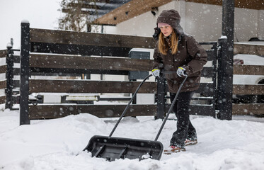 Shoveling snow from a driveway after a heavy snowfall, woman with a snow shovel