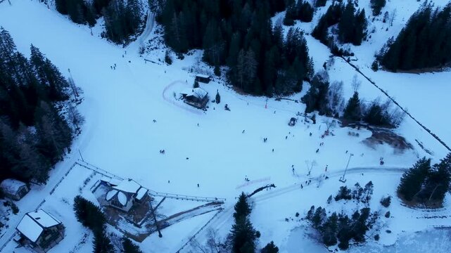 Aerial drone footage of a frozen lake in Champex, Switzerland, during winter. People ice skating surrounded by snowy alpine scenery. Shot in 4K using a DJI Mini 2.