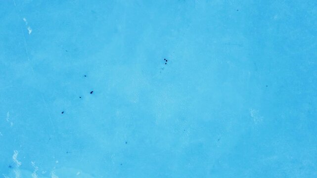 Top-down aerial drone footage of a frozen lake in Champex, Switzerland, with people ice skating in winter. Shot in 4K by a professional drone pilot using a DJI Mini 2.