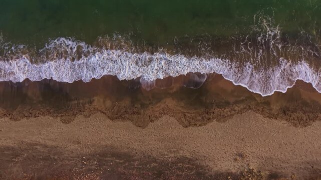 The sun sets over a peaceful beach, casting warm hues on the water as gentle waves kiss the sandy shore, creating a serene and calming atmosphere.