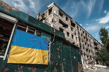 national flag of Ukraine on the wall of a house destroyed during the war in an empty city