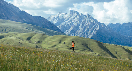 Woman runner running on the beautiful flowering grassland mountain top