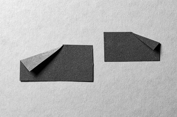 Pieces of black paper notes or sheets with folded edge dog-ear earmark and copy space for text on gray background, top view flat lay
