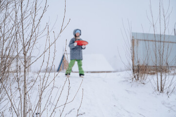 Girl in winter jacket sliding down snowy hill, playful childhood fun outdoors