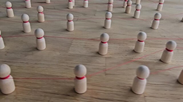 Wooden figures connected by red strings show social network patterns in a creative setup in a simple indoor environment