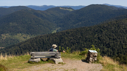randonneur assis sur un banc au sommet du Ballon d'Alsace dans les Vosges en train d'admirer les paysages de for&ecirc;ts vosgiennes
