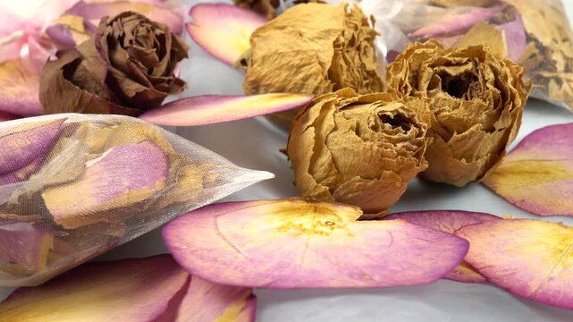 Organza sachets filled with dry rose petals, dried rose buds lie on a table, side view