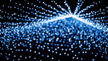 Bright blue sparkling particles exploding in a dark background with radiant light effect