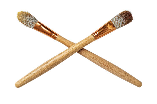 Two crossed paintbrushes with wooden handles and detailed bristles isolated on transparent background.
 - Powered by Adobe