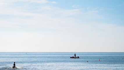 Fototapeta premium people silhouette on a boat in front of a Adriatic Sea beach during a summer day, Bibione Pineda, Venice, Italy