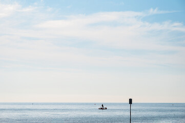 Fototapeta premium people silhouette on a boat in front of a Adriatic Sea beach during a summer day, Bibione Pineda, Venice, Italy
