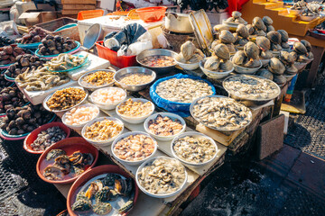 Busan fish market vendors display fresh clams, oysters, shrimp, and abalone for sale