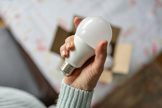 Senior woman's hands installing eco light bulb in her home
