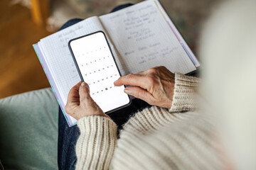 Senior woman using written notes and her mobile phone