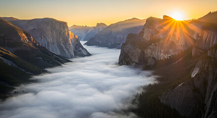 Aerial view of a sunlit valley filled with low-lying clouds, framed by towering, rugged rock formations