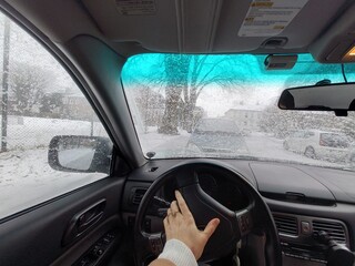 Winter driving in Germany seen from inside the car. Snow-covered streets, icy windshield, and driver&rsquo;s hand on the steering wheel reflect everyday urban transport in cold weather.